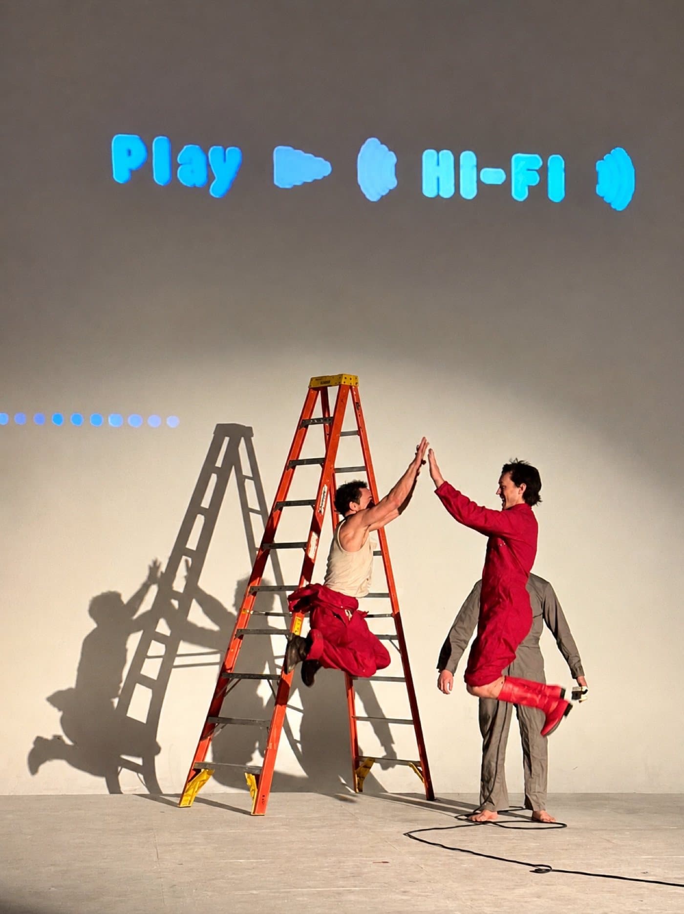 Performers jumping for a high five beside a ladder